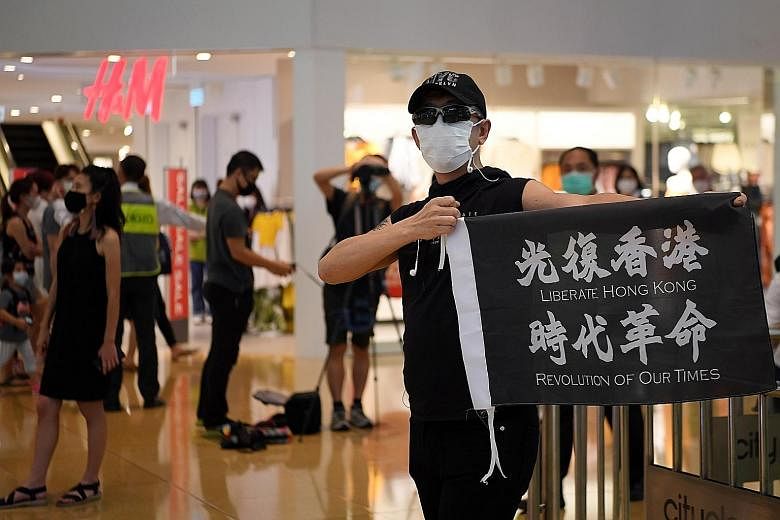 A pro-democracy demonstrator at a shopping mall in Taikoo Shing, Hong Kong, yesterday, on the first anniversary of a mass protest in the territory against a now-withdrawn extradition Bill. From June 9 last year till the end of last month, the police 