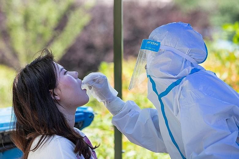 A medical worker swabbing a Wuhan University student on Monday, the first day of classes in the Chinese city. A Harvard Medical School study says the coronavirus may have been circulating in China as early as last August. PHOTO: AGENCE FRANCE-PRESSE