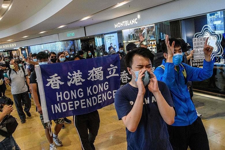 Supporters at a Hong Kong shopping mall yesterday, chanting pro-democracy slogans and defying social gathering limits imposed because of the pandemic. A group of Hong Kong students at a pro-democracy protest near their school yesterday. Students have