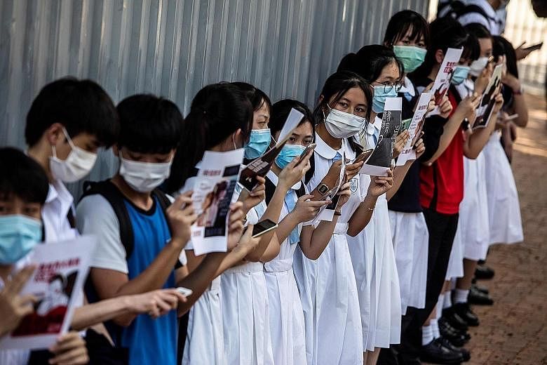 Supporters at a Hong Kong shopping mall yesterday, chanting pro-democracy slogans and defying social gathering limits imposed because of the pandemic. A group of Hong Kong students at a pro-democracy protest near their school yesterday. Students have