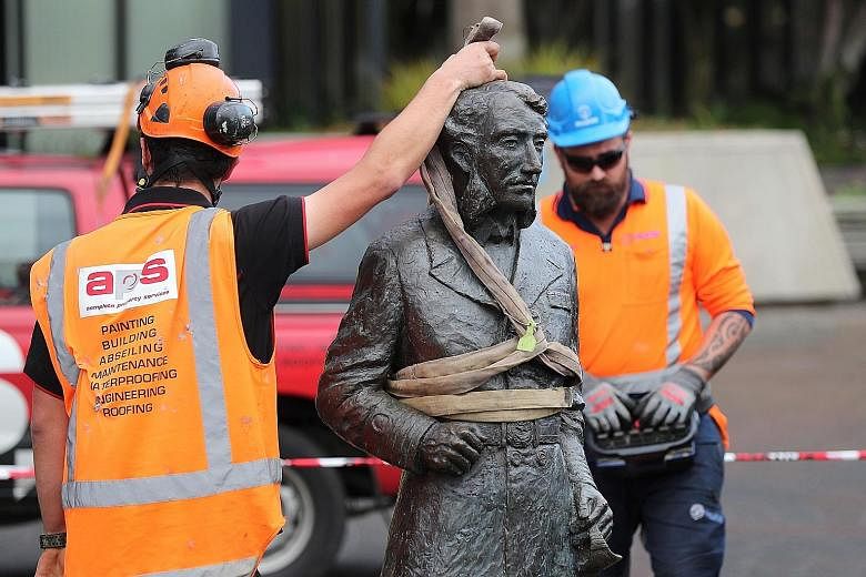 Workers removing the statue of John Hamilton yesterday in Hamilton, a city named after him in New Zealand. The British officer was accused of killing indigenous Maori people in the 19th century. PHOTO: AGENCE FRANCE-PRESSE