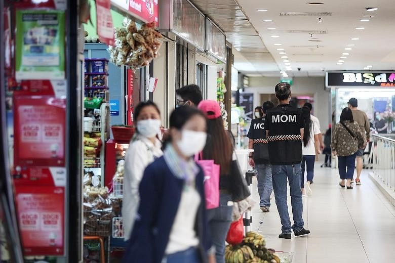 Enforcement officers from the Ministry of Manpower patrolling Lucky Plaza yesterday afternoon, with crowds notably thinner compared with the previous weekend. A new rule requiring those who want to remit money through agencies at Lucky Plaza, City Pl