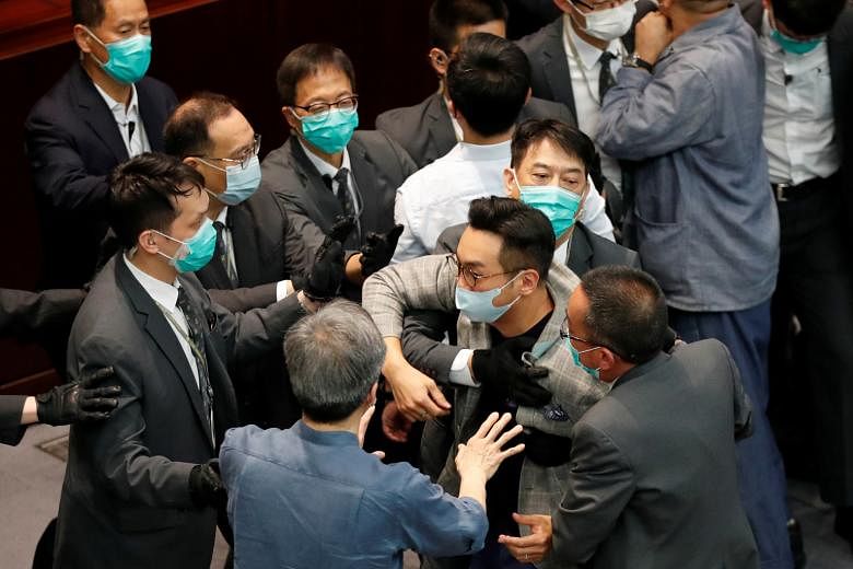 Mr Alvin Yeung (centre) being restrained by security officers at a Legislative Council meeting last month.
