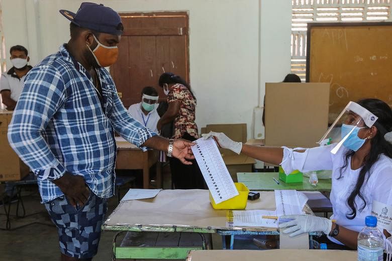 A polling officer handing a voter a ballot paper during a mock election in Negombo, Sri Lanka, last Saturday. Sri Lanka is conducting a series of mock polls across the country to test new health measures that will be implemented at polling booths and