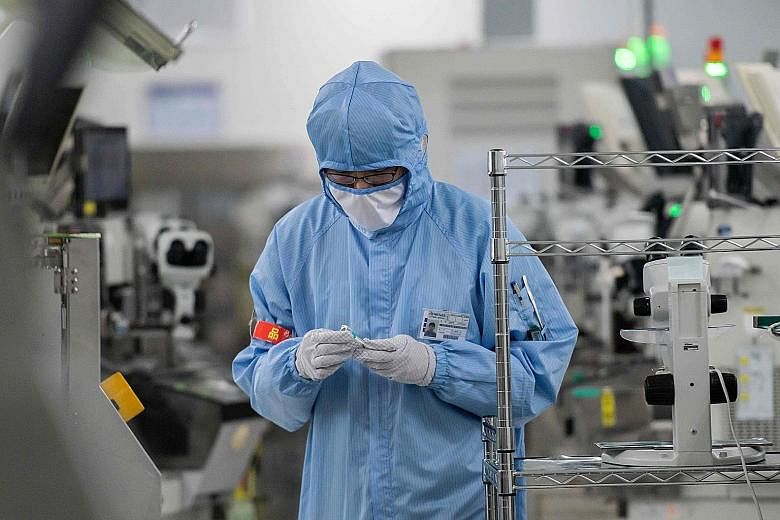 A worker at a production facility of Renesas Electronics, a global Japanese semiconductor manufacturer, in Beijing last month. The electronics industry is holding up relatively well amid the pandemic as companies adopt new technologies - including 5G