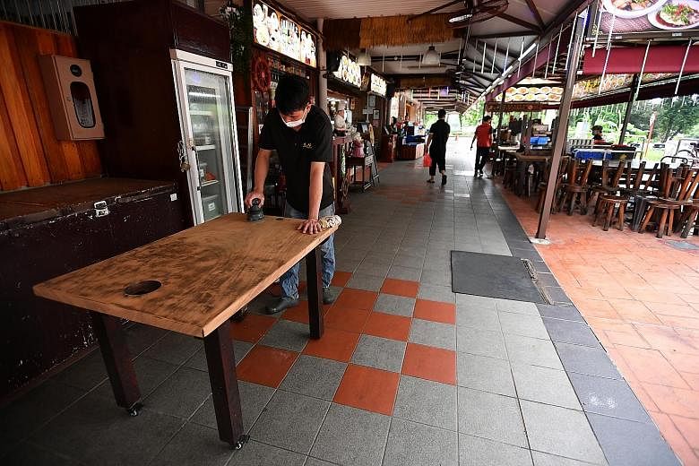 An employee of Olden Street Bak Kut Teh at Changi Village Hawker Centre cleaning the table yesterday, as eateries prepare to welcome diners from Friday, when dining in is allowed to resume.