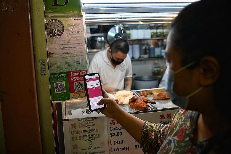 A customer paying for her meal cashlessly by scanning a QR code at Tong Fong Fatt Hainanese Boneless Chicken Rice at Bedok Food Centre on Monday. Jurong GRC MP Ang Wei Neng plans to encourage market and coffee-shop stallholders in Jurong to adopt e-p
