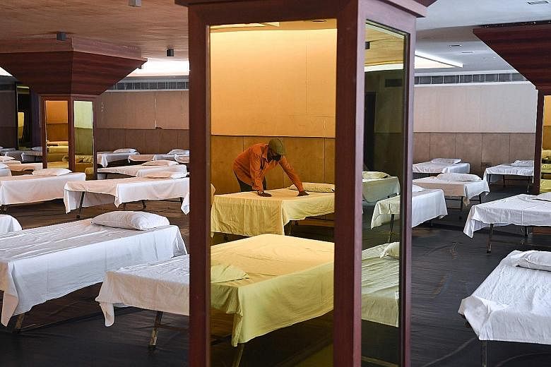 A man preparing beds at a private banquet hall in New Delhi that is being used temporarily as an isolation ward for Covid-19 patients yesterday. India's surge in new cases is threatening to overwhelm its hospitals. PHOTO: AGENCE FRANCE-PRESSE