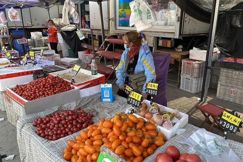 Tomato seller Ma Xiaoli (left) at Beijing's Dayanglu Market yesterday. She was allowed to continue running her stall while awaiting the results of her Covid-19 test. Most vendors at the meat section (right) of the market had packed up ahead of the ma