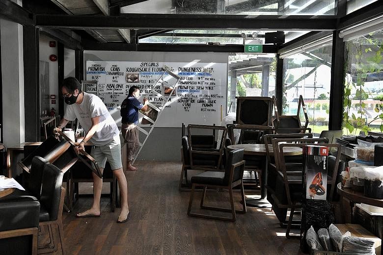 Naked Finn owner Tan Ken Loon (left), 45, setting up the tables and chairs in his eight-year-old seafood restaurant at Gillman Barracks yesterday as he got ready for the start of phase two tomorrow, when food and beverage outlets can restart dine-in 