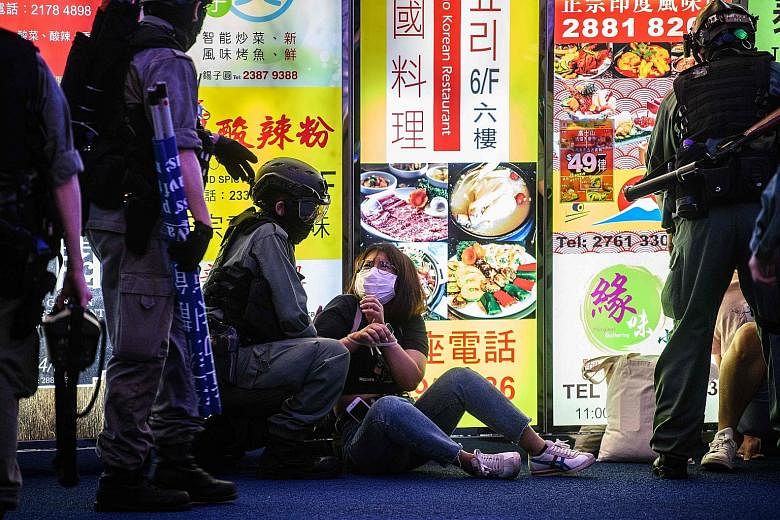 Police detaining a woman at a pro-democracy protest in Causeway Bay on June 12. Protests in Hong Kong have morphed into a call for police accountability, and Beijing says the new national security law is needed to end political unrest there. PHOTO: A