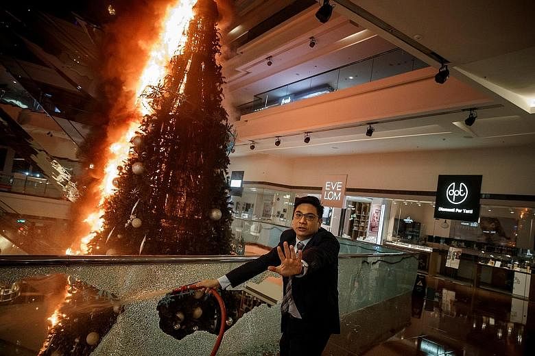 A security officer trying to extinguish a fire set by protesters at the Festival Walk mall in Hong Kong last November. PHOTO: REUTERS