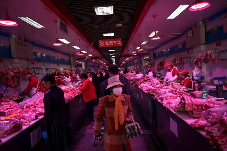 A worker moving produce at the closed Xinfadi market in Beijing. The outbreak last December in Wuhan also started in a market. Above: Chefs waiting to be tested for Covid-19 in Beijing yesterday. Right: Customers buying live seafood at a supermarket 