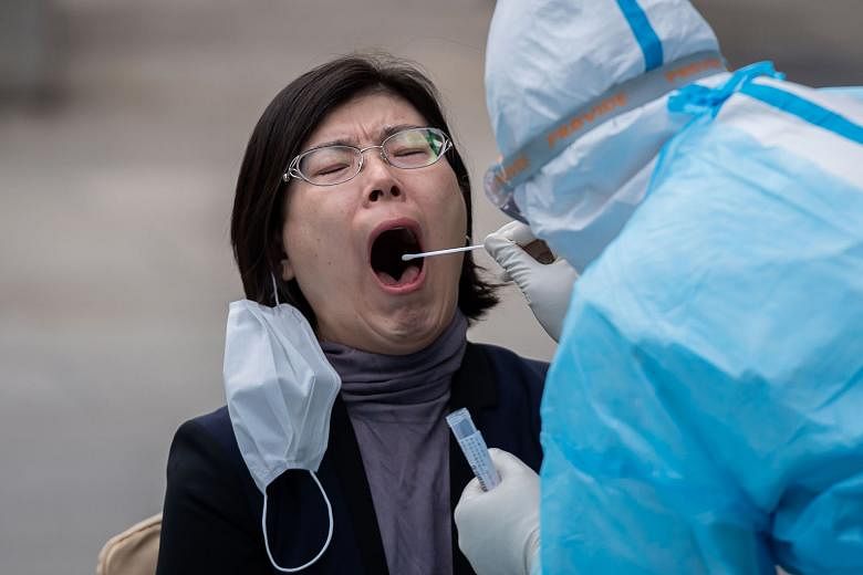 A woman having a swab sample taken. The fresh coronavirus outbreak in Beijing has sparked a massive trace and test operation. Medical staff off to a testing facility for people who live near or who have visited the Xinfadi market where the cluster em