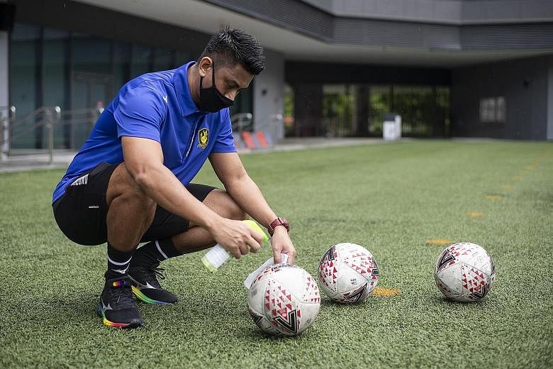 From left: Tampines Rovers players Amirul Adli and Baihakki Khaizan, together with assistant coach Mustafic Fahrudin, warming up at Our Tampines Hub yesterday. Below: Sofiyan Abdul Hamid, one of Tampines' assistant coaches, disinfecting balls between