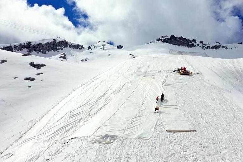Workers unravelling a vast tarpaulin down the slopes of the glinting Presena glacier. The glacier in northern Italy has lost over one-third of its volume since 1993 and the tarpaulin is meant to protect the alpine ice from global warming. Once the sk