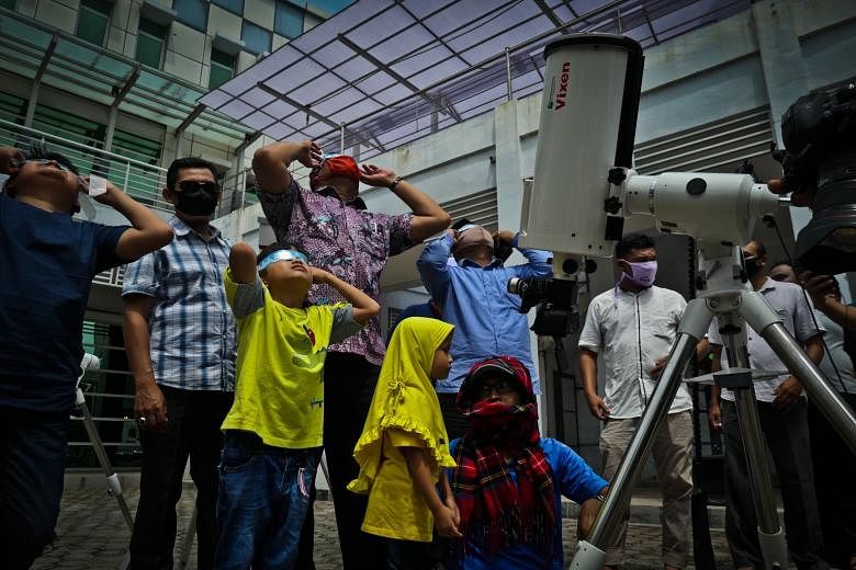 INDONESIA: Avid skywatchers in Banda Aceh gathering to witness the "ring of fire" eclipse, a rare event. CHINA: Protective glasses were added to the now-compulsory masks as people gazed at the partial solar eclipse from Beijing's Temple of Heaven par