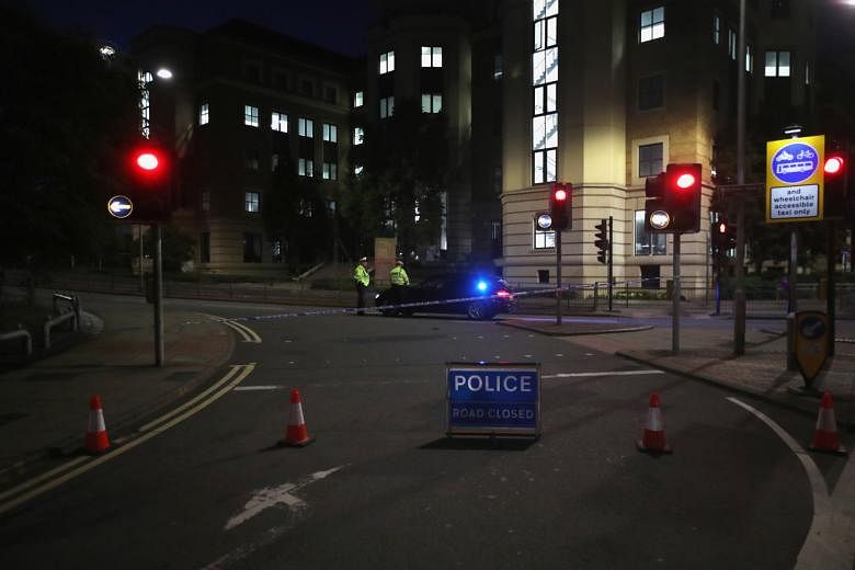 A police cordon (above) at the scene of the stabbings in Reading, England, last Saturday night. Police officers (below) outside a doorway of a block of flats in Reading where the suspect in the stabbing incident is believed to have lived. PHOTOS: REU