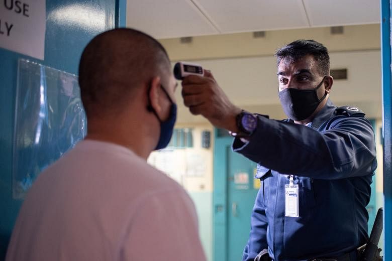 A prison officer checking an inmate's temperature in his cell. Some core rehabilitation programmes have resumed.