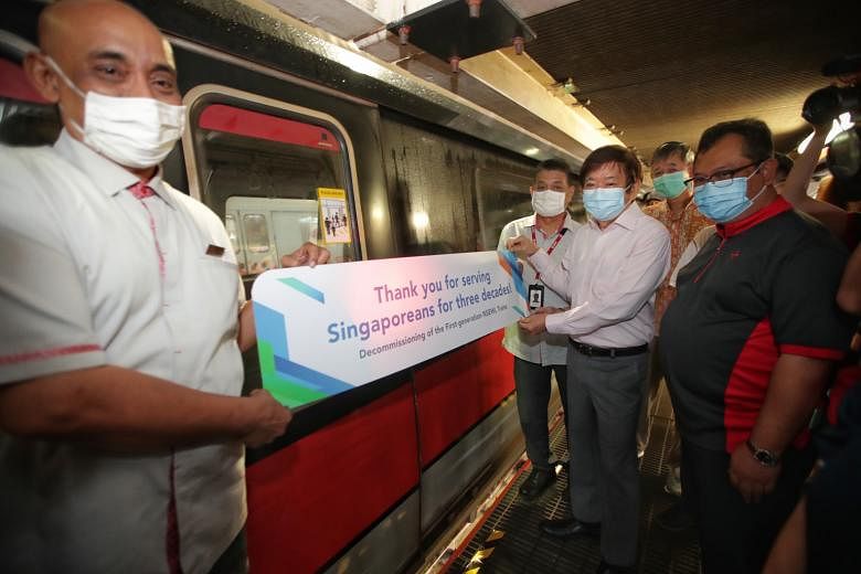 Transport Minister Khaw Boon Wan and train captain Mayudin Saad putting a sticker on a decommissioned train at the Bishan Depot yesterday. With them were (clockwise, from second left) train captain Ling Ghee Choon, retired Land Transport Authority st