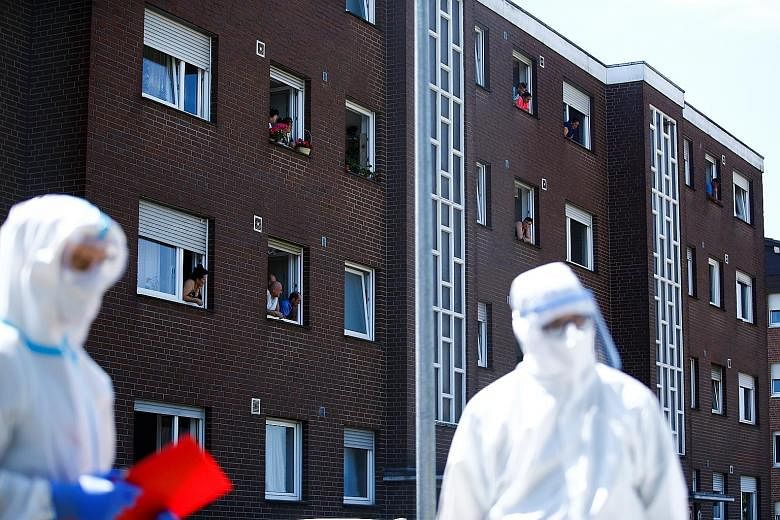 Employees of the Toennies meat processing factory, where an outbreak has infected more than 1,500 workers, leaning out of the windows of their homes in Guetersloh, Germany, yesterday. PHOTO: REUTERS
