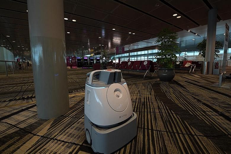 A robot vacuum cleaner doing its job in the transit holding area at Changi Airport's Terminal 3 yesterday. (From left) Changi Airport Group (CAG) chief executive Lee Seow Hiang, Transport Minister Khaw Boon Wan, CAG senior vice-president for passenge