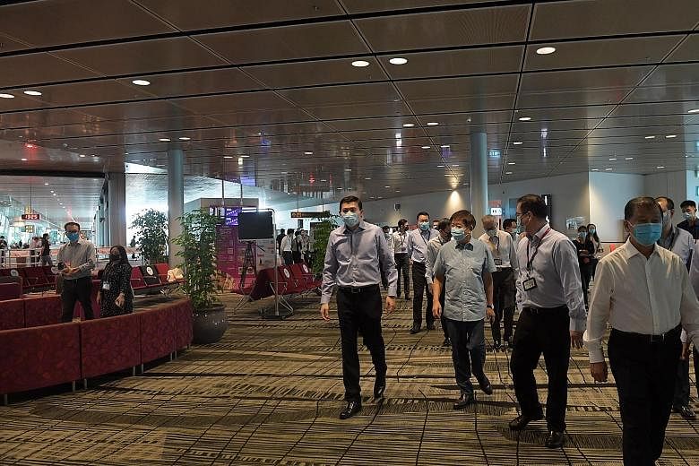 A robot vacuum cleaner doing its job in the transit holding area at Changi Airport's Terminal 3 yesterday. (From left) Changi Airport Group (CAG) chief executive Lee Seow Hiang, Transport Minister Khaw Boon Wan, CAG senior vice-president for passenge