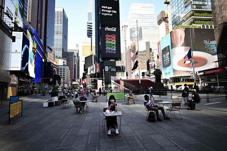 Times Square in New York City on Monday. The metropolitan area was the last region to move into phase two of New York state's economic reopening plan. PHOTO: AGENCE FRANCE-PRESSE A busy barber shop and a Bloomingdale's department store in New York Ci