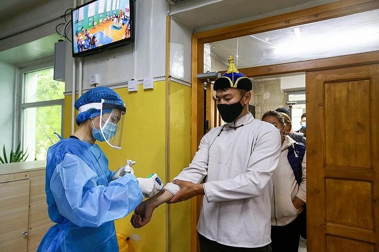 A man with a face mask has his temperature checked as he arrives to vote at a polling station in Ulaanbaatar, the capital of Mongolia. Medical staff were also present yesterday to hand out disinfectant and single-use plastic gloves to voters who were