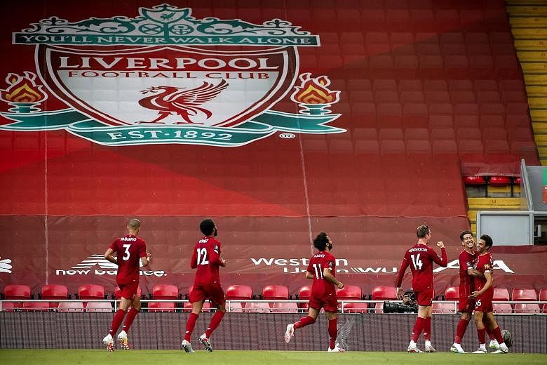 Liverpool players celebrate breaking the deadlock before an empty Anfield Road stand after Trent Alexander-Arnold (right) scored from a direct free kick. Liverpool beat Crystal Palace comprehensively 4-0.