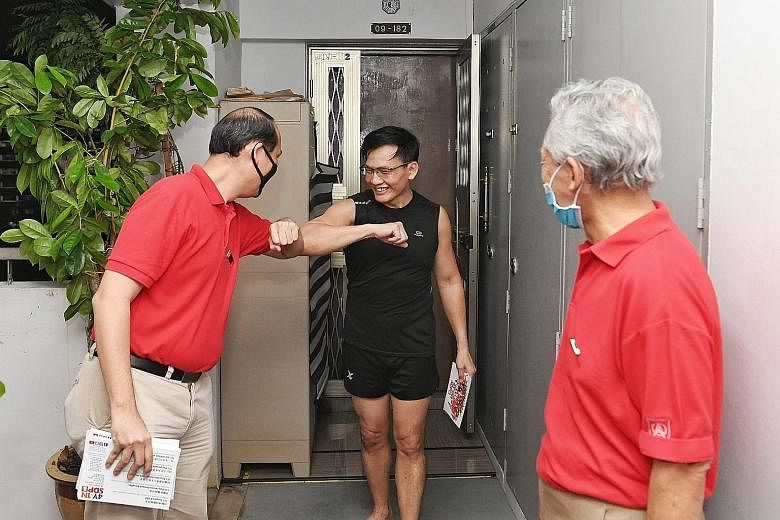 Mr Bryan Lim, a member of the Singapore Democratic Party (SDP), greeting a resident in Block 562 Choa Chu Kang Street 52 with an elbow bump during a house visit yesterday while another SDP member looked on. The block is located in Marsiling-Yew Tee G