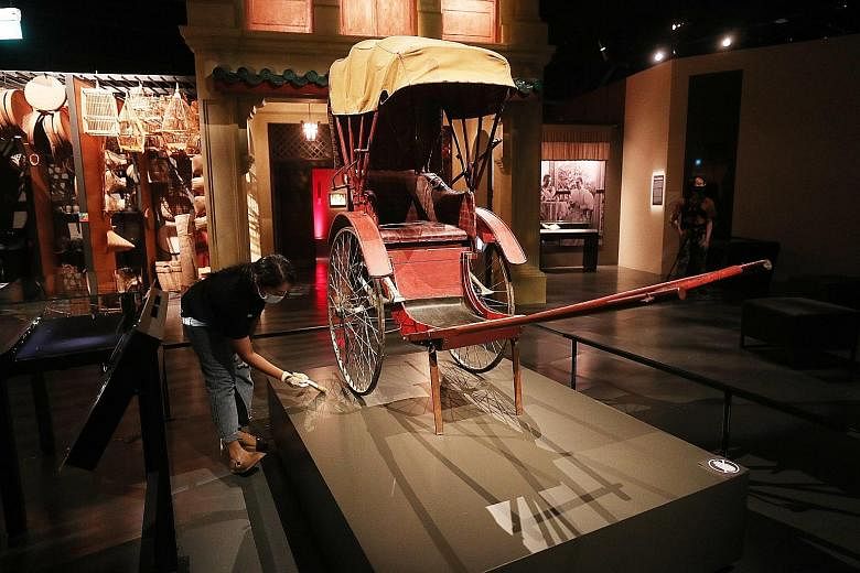 A collection officer dusting a rickshaw at the National Museum of Singapore on Tuesday, in preparation for the museum's reopening today. The writer says that with still no end in sight to the Covid-19 pandemic, museums will have to not only find ways