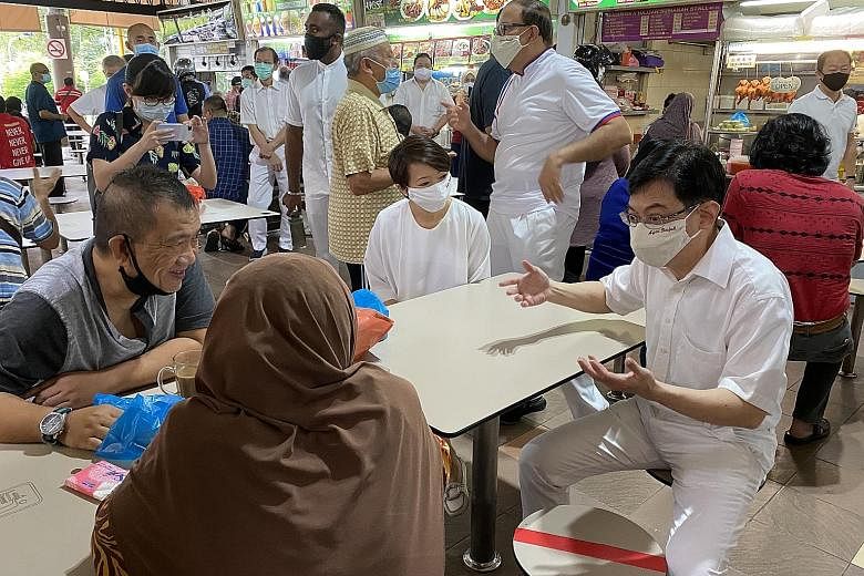 (From right) Deputy Prime Minister Heng Swee Keat (seated), Communications and Information Minister S. Iswaran and West Coast GRC MP Foo Mee Har met members of the public around Teban Market Place yesterday.