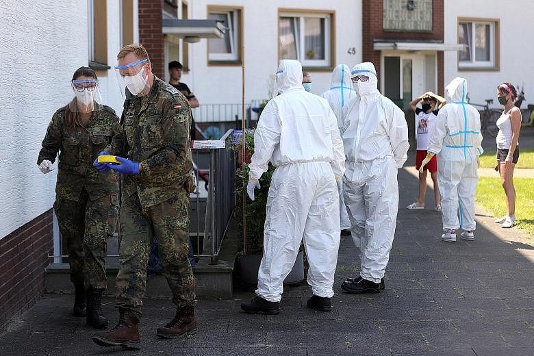Paramedics from a mobile testing unit of the German Red Cross and the German army preparing to collect virus test samples from employees of meat-processing company Toennies in a quarantined building in Guetersloh, Germany, on Tuesday. PHOTO: EPA-EFE