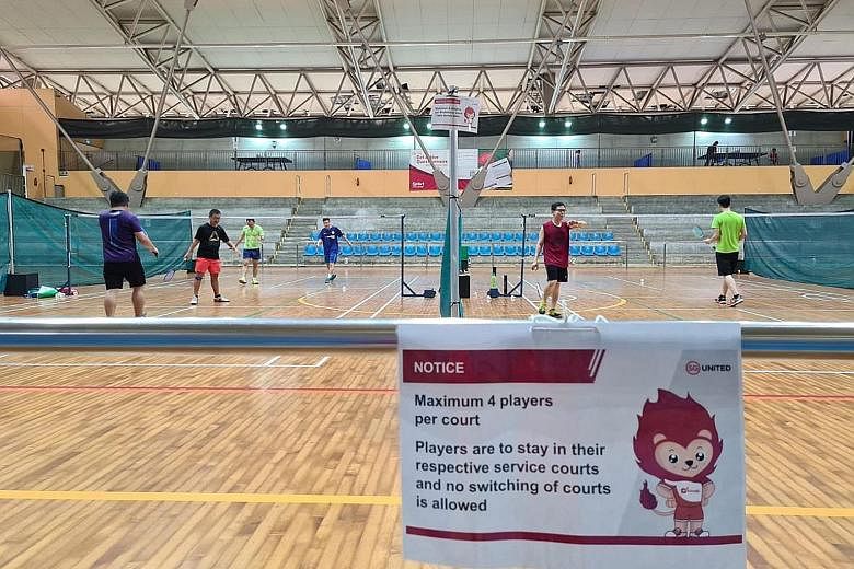 Badminton players in action at the Yishun Sports Hall. Signs reminding players of the safe management measures are posted clearly around SportSG's facilities. PHOTO: SPORT SINGAPORE