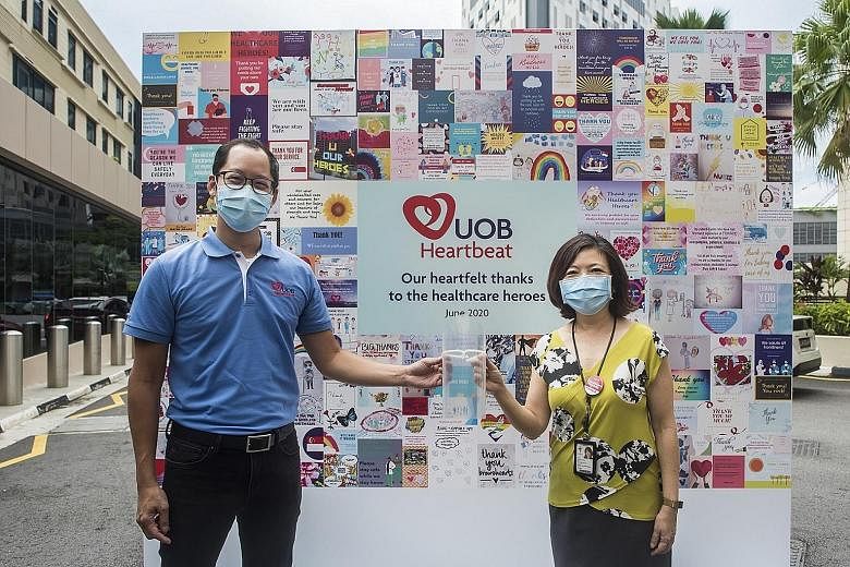Mr Eric Lim, UOB head of group finance, and Ms Loh Shu Ching, executive director at Tan Tock Seng Hospital's division of central health, with a 3D-printed face shield to be given to front-line healthcare workers at the hospital and the National Centr