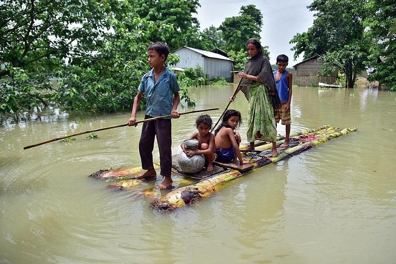 Villagers making their way on a makeshift raft through a flooded field to reach a safer place in the north-eastern Indian state of Assam yesterday. Torrential rain hit at least 23 of the state's 33 districts.