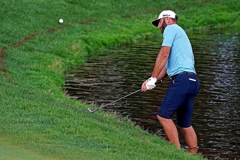 Dustin Johnson playing the second shot at the 15th hole with his feet in the pond on Sunday. He went on to save par and win by one shot.