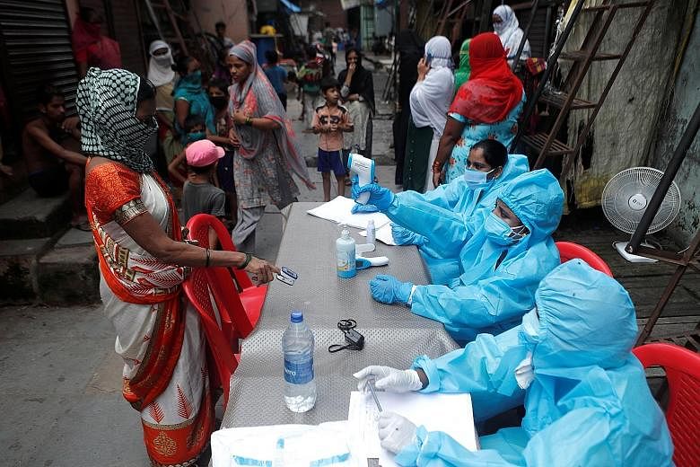 A healthcare worker checking the temperature of a woman in Mumbai yesterday, during a medical campaign to curb the spread of Covid-19. PHOTO: REUTERS