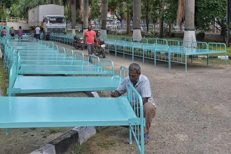 Workers assembling metal cots on Monday outside Bangalore's Koramangala indoor stadium, which is being converted into a temporary care centre with over 250 beds, in a bid to contain the spread of Covid-19.