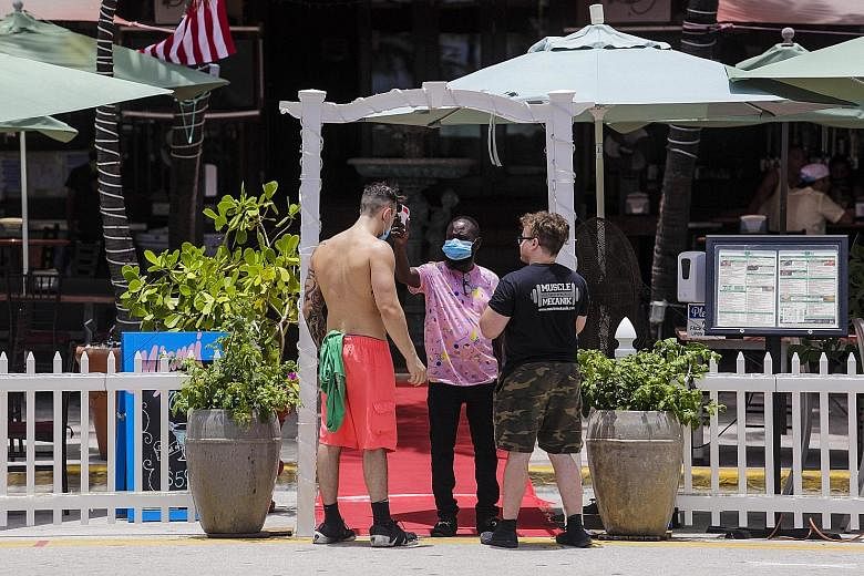 A restaurant worker checking a customer's temperature in Miami Beach, Florida, on Sunday. The southern US state saw 5,266 new Covid-19 cases on Monday.