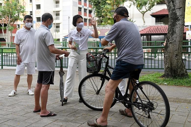 Dr Ang Yong Guan, the PSP's candidate for Marymount, giving out face masks to residents during his walkabout in Sin Ming Road yesterday. The WP's Ms Tan Chen Chen, who is contesting in Punggol West, giving her speech at St Anthony's Canossian Primary