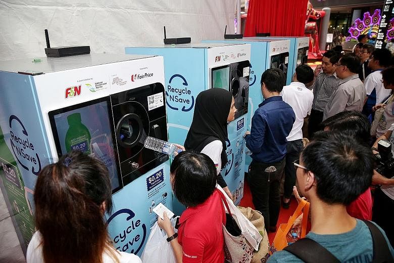 The "reverse" vending machines during their launch at Our Tampines Hub last October. The older machines (above) dispense a 20-cent FairPrice discount voucher for every 20 containers deposited. The new machines offer more reward choices, including fre