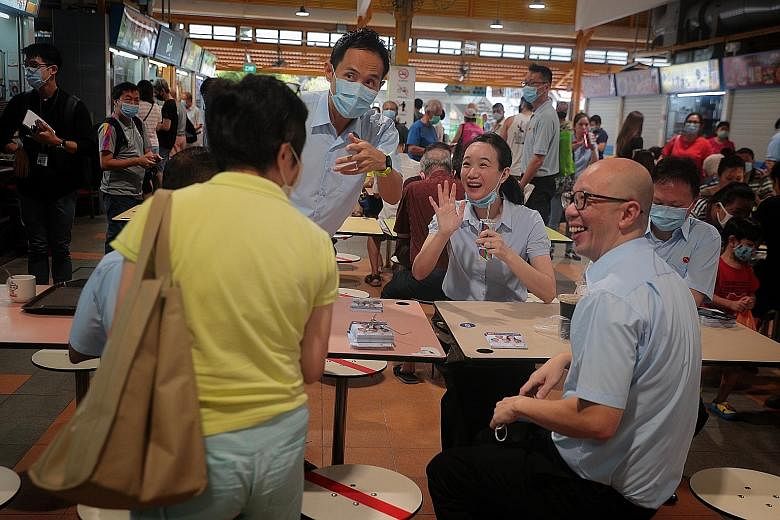 Workers' Party candidates for East Coast GRC (from left) Abdul Shariff Aboo Kassim (obscured), Kenneth Foo, Nicole Seah, Terence Tan and Dylan Ng greeting a well-wisher during a walkabout in Bedok yesterday.