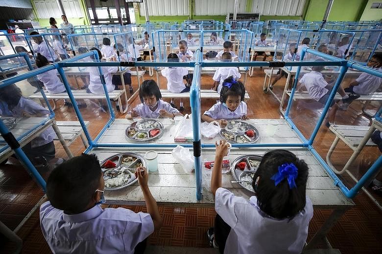Students eating lunch together, separated by plastic sheets, at a school in Bangkok yesterday after months of distance learning.