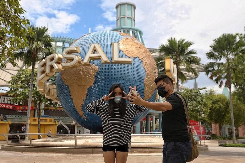 Left: Mr Joseph Teng, 31, and Ms Nu Mai Anh, 24, outside Universal Studios Singapore yesterday. With fewer visitors, they could enjoy some popular rides several times. Top: People waiting to get into the casino at Resorts World Sentosa yesterday. Abo