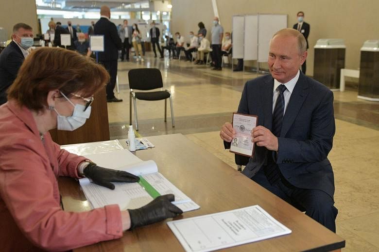 Russian President Vladimir Putin showing his passport to a member of a local electoral commission in Moscow ahead of casting his ballot in Wednesday's nationwide vote on constitutional reforms. The constitutional amendments were approved by just over