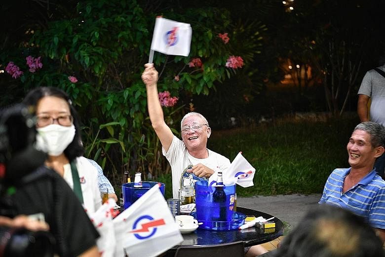 A boy gets a party flag from PAP East Coast GRC candidate Maliki Osman during a walkabout in Simei. WP team members (from left) Nicole Seah, Terence Tan and Abdul Shariff Aboo Kassim at Bedok Central yesterday. A resident waving a People's Action Par