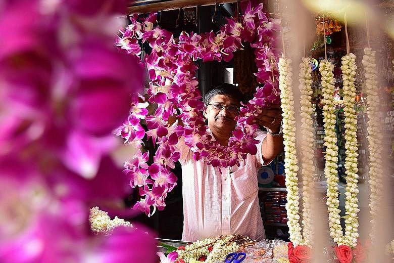 While vendors such as Mr Rajakumar Chandra (top), who sells flower garlands, may receive fewer orders from political parties this year, others like Ms Sarah Tang (above right) and Ms Alison Schooling of graphic design studio Sarah and Schooling are e