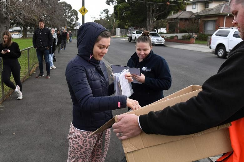 A woman in Melbourne collecting a kit ahead of testing for the coronavirus on Thursday. Around 300,000 people in the Australian city are back in lockdown under the threat of fines and arrest.